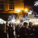 People surrunding a christmas market stall at night time