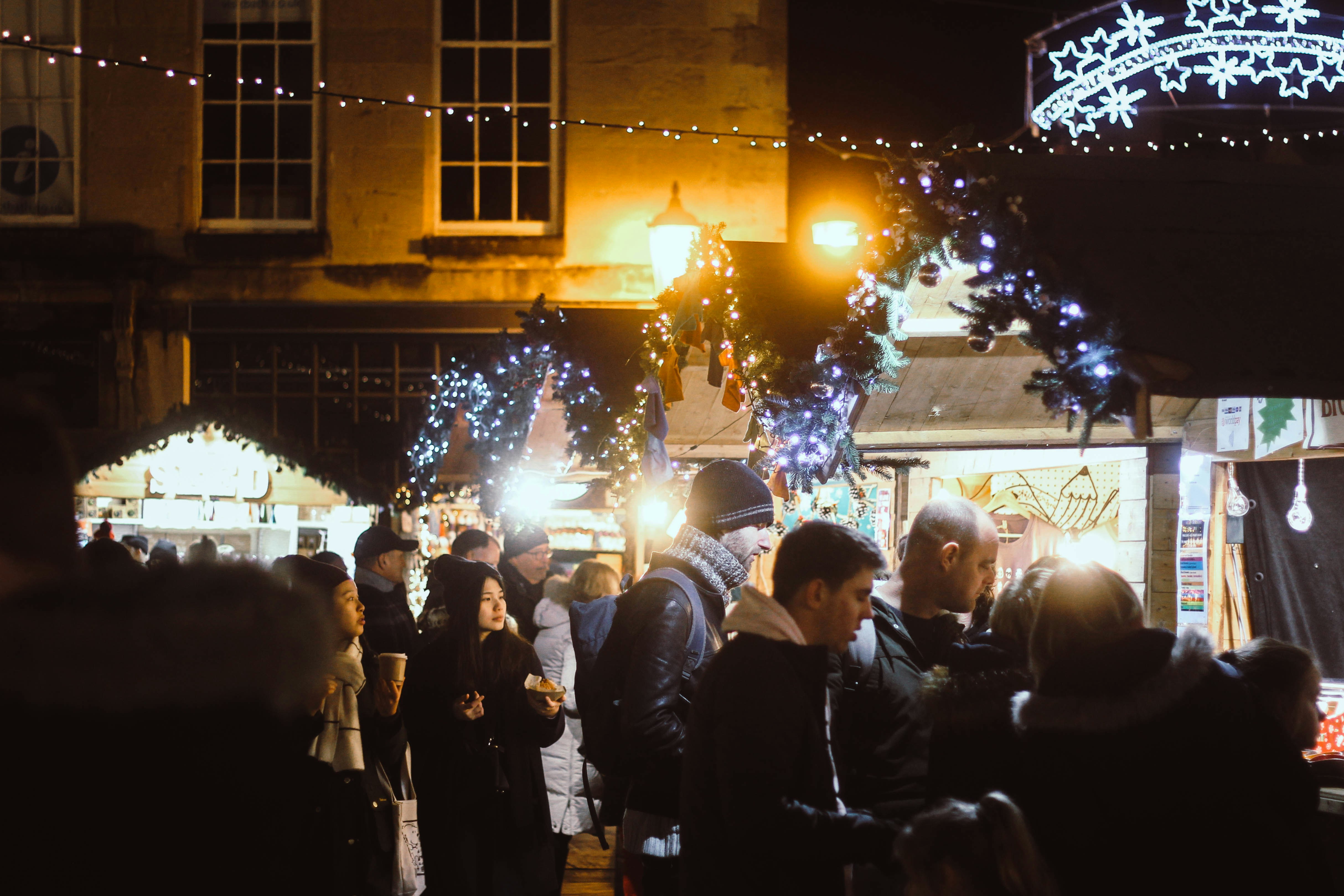 People surrunding a christmas market stall at night time
