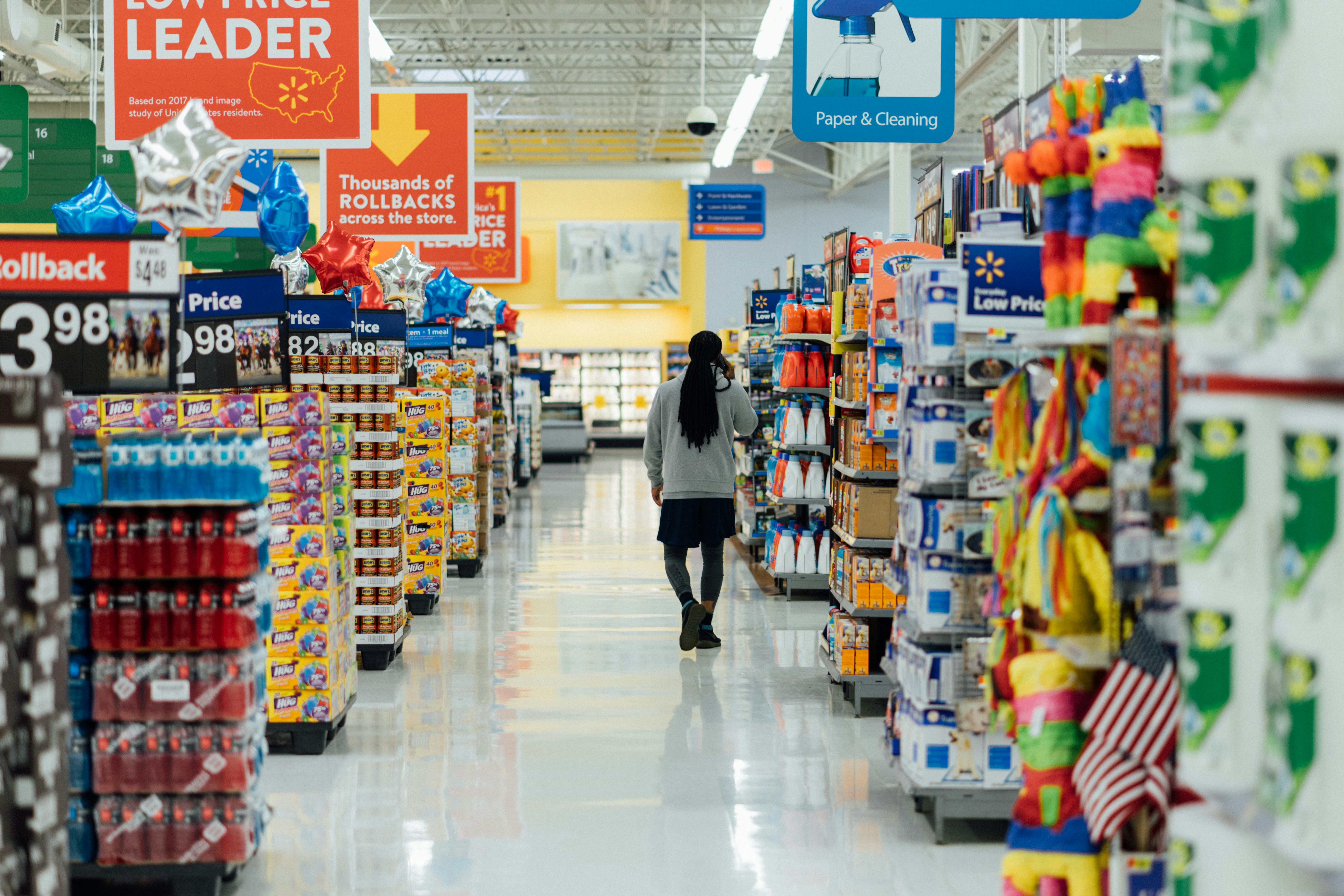 Woman walking down aisle in supermarket.