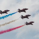 red arrows flying with coloured smoke trails