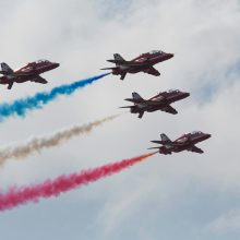 red arrows flying with coloured smoke trails