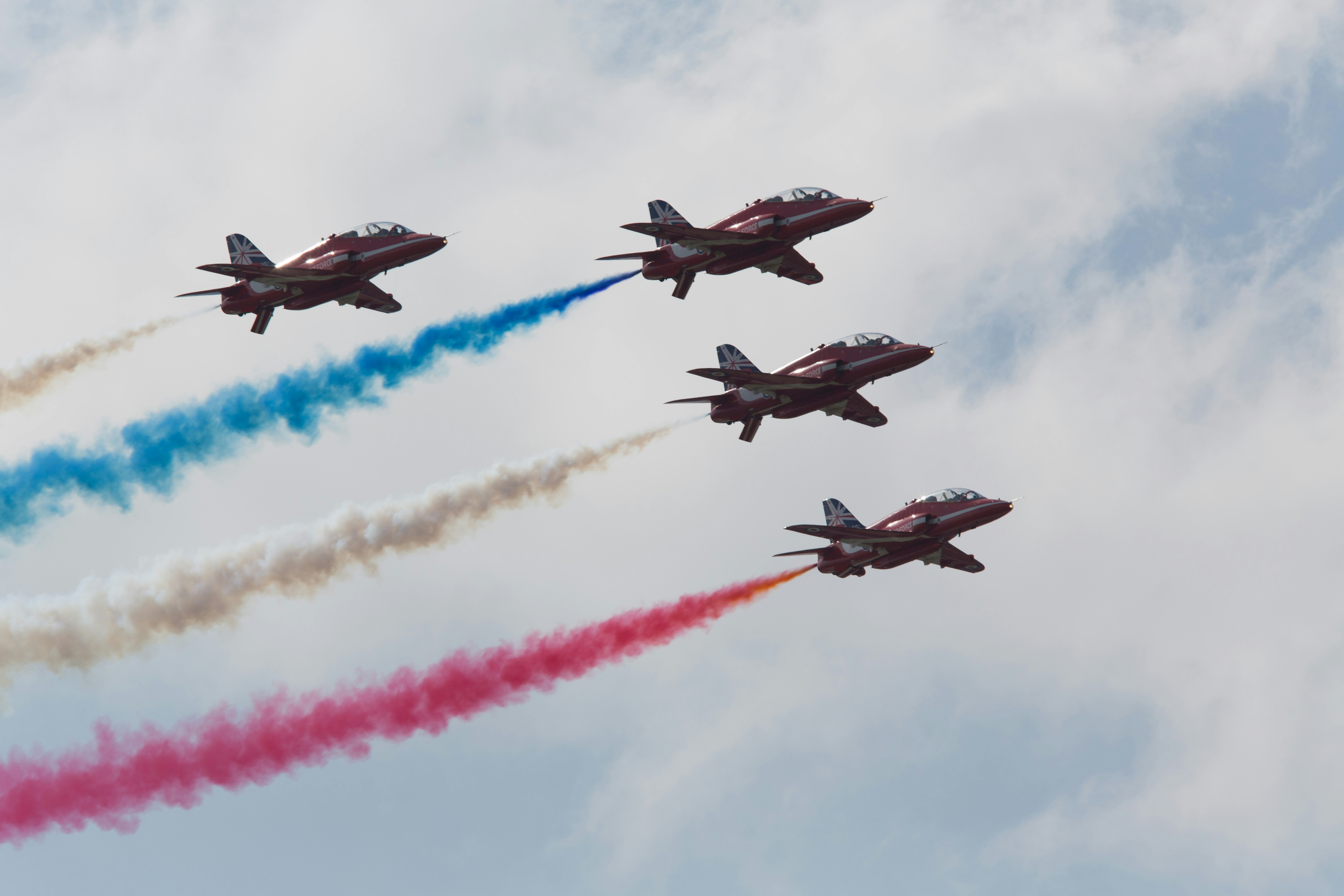 red arrows flying with coloured smoke trails
