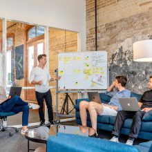 4 men gathered round a white board
