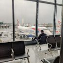 man sat by window at heathrow airport with plane in background