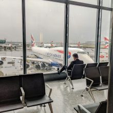 man sat by window at heathrow airport with plane in background