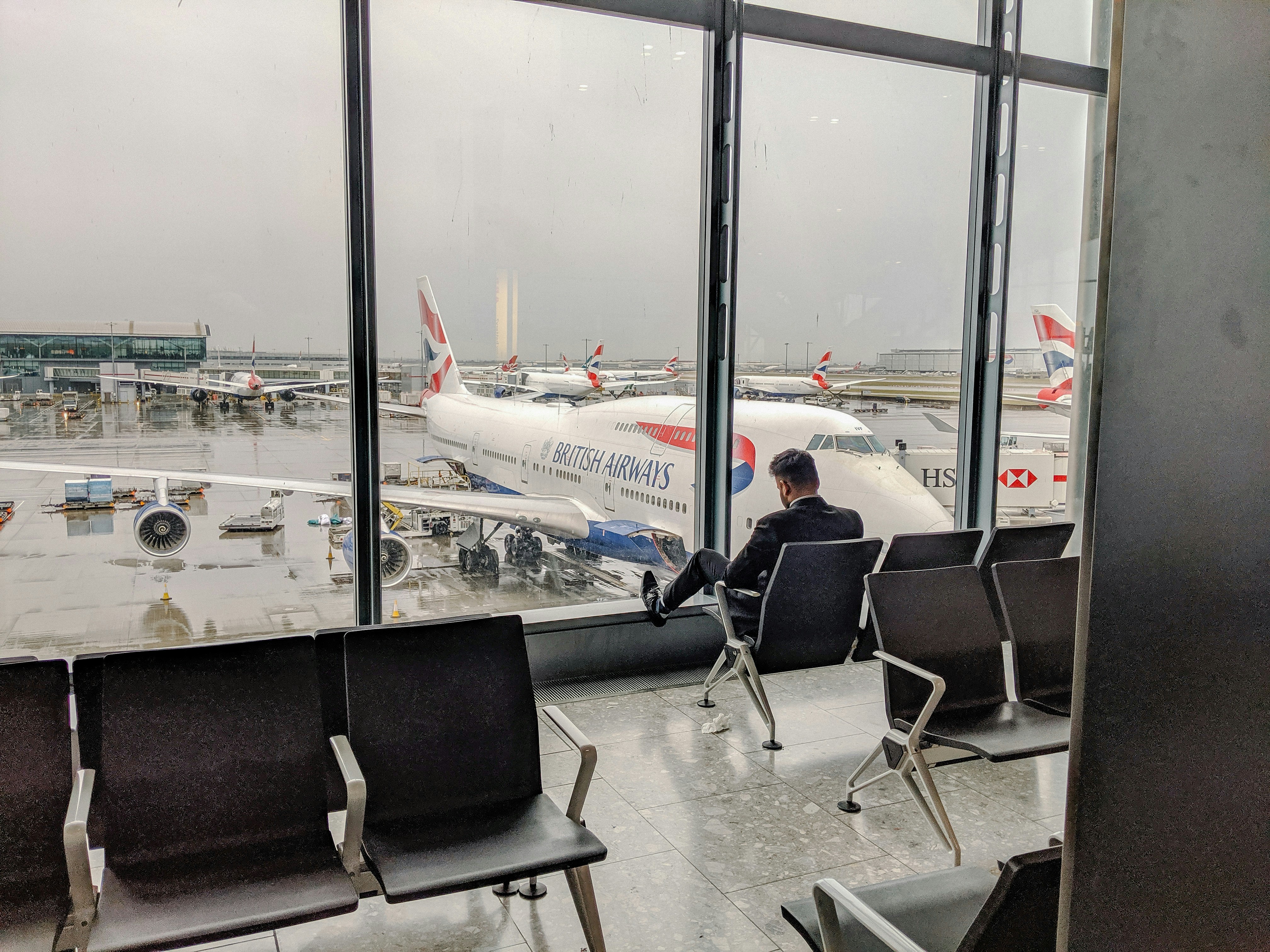 man sat by window at heathrow airport with plane in background