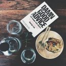 A book, cup and drinking glasses on a wooden table