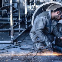 male welding metal on floor