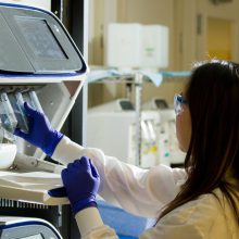 woman in lab working a machine with test tubes