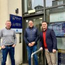 Three men in casual way standing at the door to an office