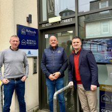 Three men in casual way standing at the door to an office