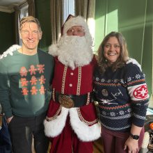 A mand and a woman in Christmas jumpers with Santa