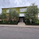 two storey school building behind a row of trees