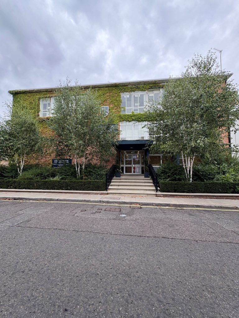 two storey school building behind a row of trees